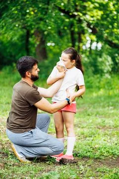 Side view of middle-aged man father squatting on hams, wiping daughters nose Stock Photos
