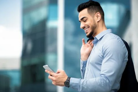 Side view of middle-eastern young entrepreneur checking emails on cellphone Stock-Fotos