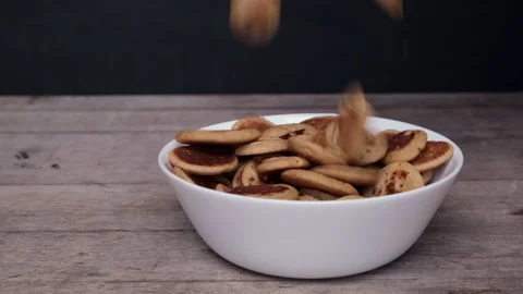 Side view mini pancakes falling in bowl in slow motion. Tiny pancake cereal 動画素材 131106699