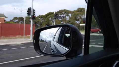 A side-view mirror of a moving car with a blurry row of suburban houses. Stock Footage 275827656
