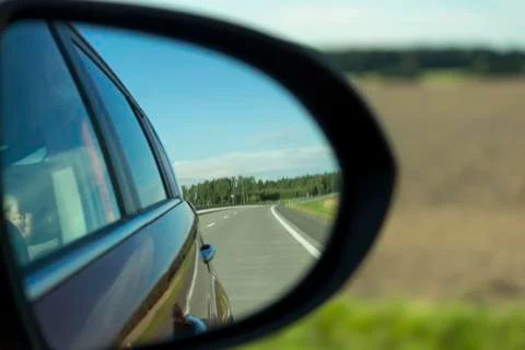 Side view mirror reflection of two-lane winding road in forest. Baby boy Stock Photos