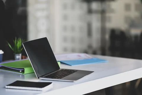 Side view of mock up laptop computer and document file on conference table. Stock Photos