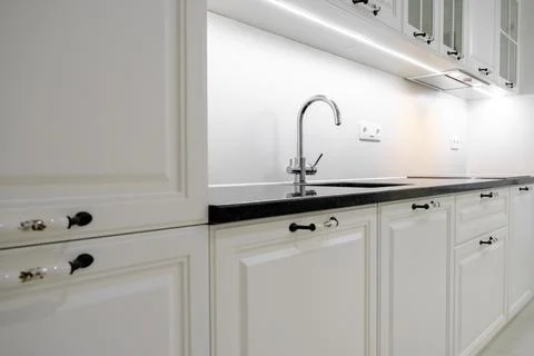 Side view modern and elegant kitchen with white drawers and cupboards, black  Stock Photos