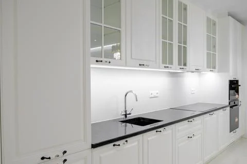 Side view modern and elegant kitchen with white drawers and cupboards, black  Stock Photos