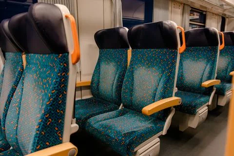 Side view of modern blue patterned train seats with wooden armrests inside clean Foto stock