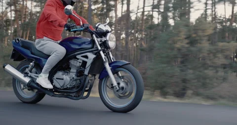 Side view: Motorcyclist rides along forest on cloudy day Stock Footage 146361002