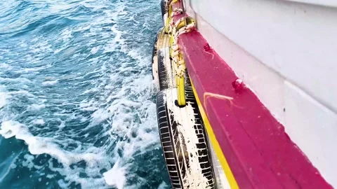 Side view of moving boat hull with tire fenders splashing through sea water Stock Footage 340533326