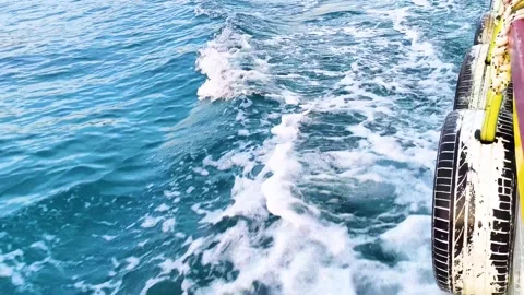 Side view of moving boat hull with tire fenders splashing through sea water Stock Footage 340533328