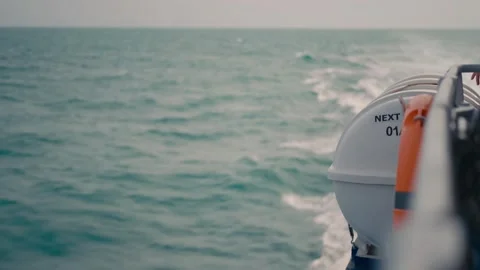 Side view from a moving boat showing ocean waves and white life raft 動画素材 332720372