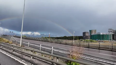 Side View from a Moving Car with Highway, Rainbow, and Apartment Buildings Stock Footage 347683325