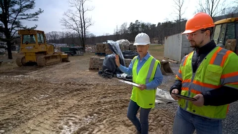 Side view moving with woman engineer and job foreman as they walk through the Stock Footage 127123256