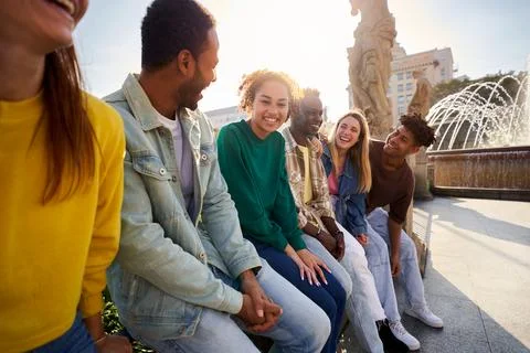 Side view of multiethnic group of Erasmus friends ganging out outdoors having Stock Photos
