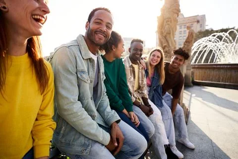 Side view of multiethnic group of Erasmus friends ganging out outdoors having Stock Photos