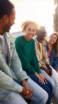 Side view of multiethnic group of Erasmus friends ganging out outdoors having Stock Photos