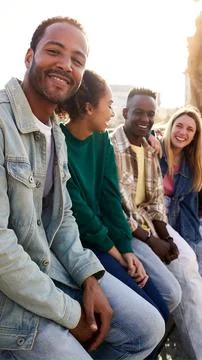 Side view of multiethnic group of Erasmus friends ganging out outdoors having Stock Photos