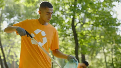 Side View of Multiethnic Young Man Using Trash Picker While Collecting Garbage Video stock 235370425