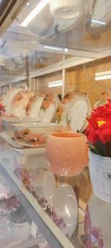 Side view of multiple ceramic plates and mug on displays in dishware store. Photos