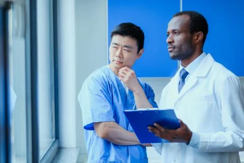 Side view of multiracial group of doctors in medical uniforms with folder in  Stockfoto's