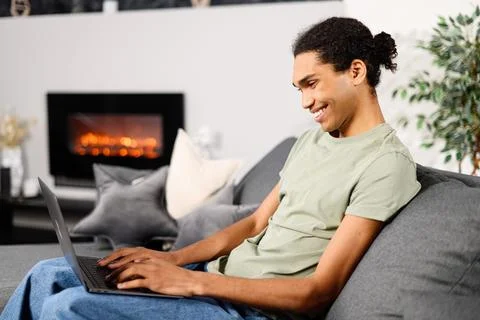Side view of the multiracial young guy uses a laptop for a video call at home Stock Photos