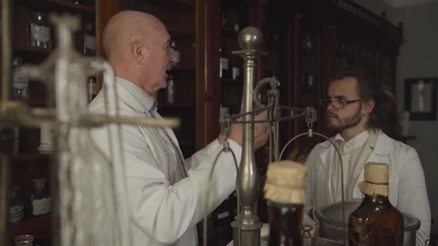Side view of old baldheaded pharmacist holding ancient flask and test tube and Stock Footage 120722295