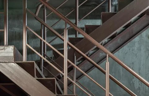 Side view of Old metal steps with handrails against concrete wall background. Foto stock