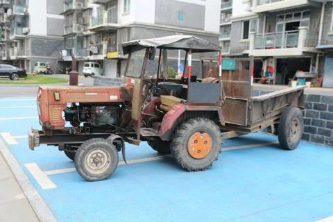 Side view of old red tractor with cargo trailer parked on blue court in res.. Stock Photos