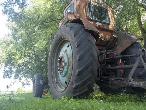 Side view of an old rusty tractor standing on green grass on a Sunny day. Rur Stock Photos