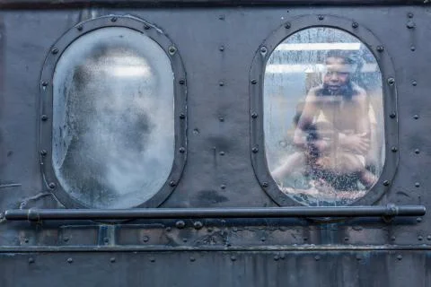 Side view of old train cabin window with reflection of two children Stock Photos