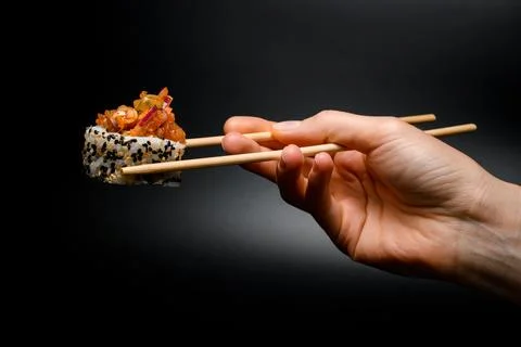Side view of one piece of roll with caramelized onion, raw fish, sesame and rice 스톡 사진