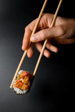 Side view of one tasty roll Hawaii in hand holding with wooden chopsticks. Stock Photos