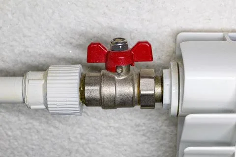 Side view of opened radiator switch with red handle connected to steel heat.. Stock Photos