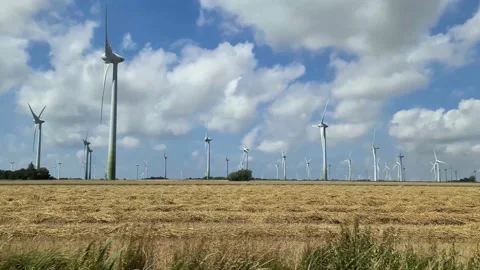 Side view out of a car driving along a big windmill park producing clean ener Stock Footage 158678511