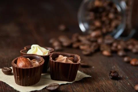 Side view of overturned glass jar with coffee beans and chocolate candies on Stock Photos