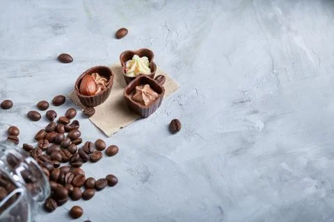 Side view of overturned glass jar with coffee beans and chocolate candies on Stock Photos