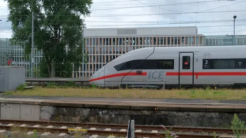 Side view of passenger express train passing modern glass office building Video stock 337404980