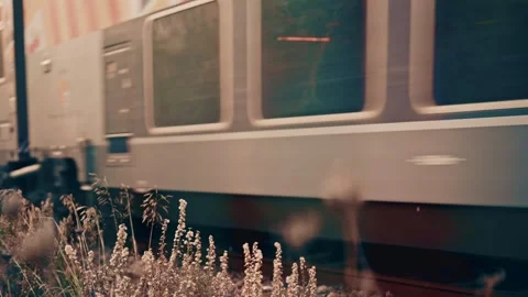 Side view of a passenger train moving along railway tracks through an urban Stock Footage 325773657