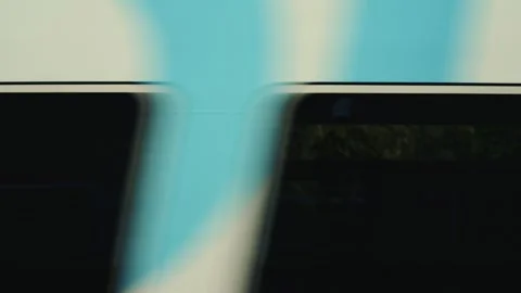 Side view of a passenger train moving past a blue fence near the railway tracks Stock Footage 325808214