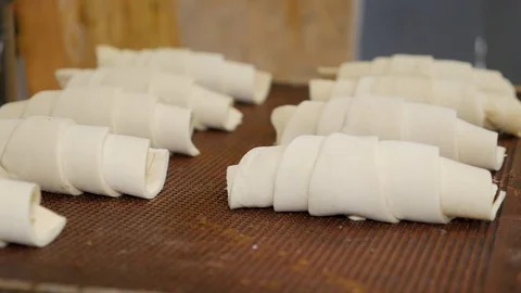 A side view of a pastry chefs hands placing raw croissants onto a baking tray Stock Footage 108097235
