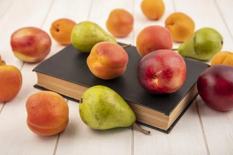 Side view of pattern of fruits as peach and pear on closed book and on wood.. Stock Photos