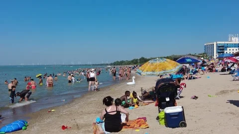 Side View People On Beach Packed With Energy Windmills In Distance And Beach Video stock 249955569