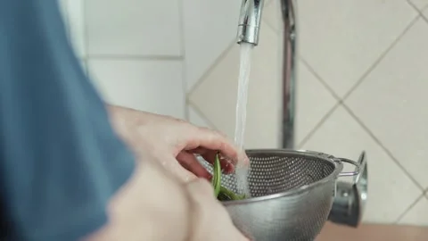Side view of a person draining water from freshly rinsed green beans Stock Footage 343555534