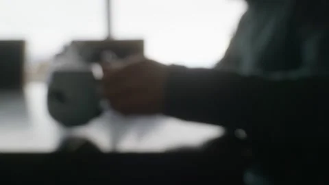 Side view of person on phone drinking coffee at table; backlit out of focus Stock Footage 248026829