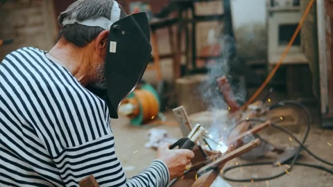 Side view of person in a welding helmet welds metal products on the street. Stock Footage 242992008