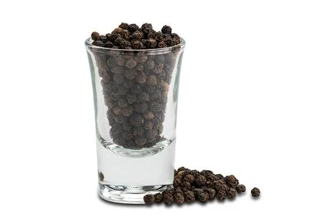 Side view pile of black pepper seeds and black peppers seeds in small glass o Stock Photos