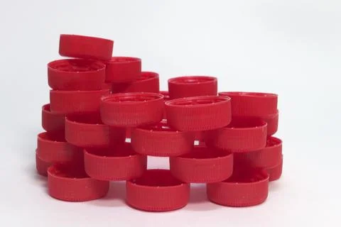 Side view of the pile of red ribbed plastic bottle caps, folded into the in.. 库存照片
