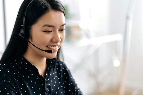 Side view of a pleasant, satisfied young asian woman with headset, freelancer Photos