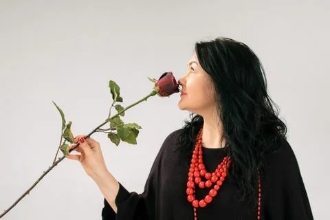 Side View of Plus Size Model in Black Dress and Ethnic Necklace Sniffing Red Stock Photos