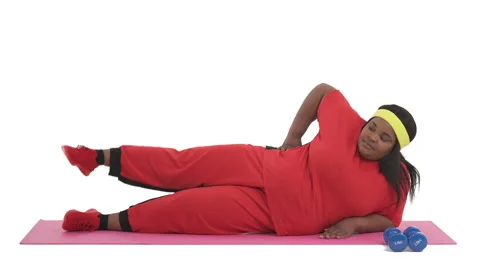 Side view portrait of african plus size woman doing supine side leg raises Stock Footage 134575818