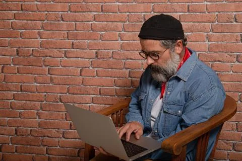 Side view portrait of bearded man in denim shirt sitting on wooden chair work Stock Photos