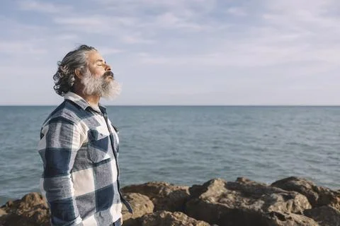 Side view portrait of a bearded man breathing fresh air on the beach Stock Photos